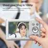 A hand holding a digital camera displaying a young woman with headphones on its screen, with text overlays promoting its vlog capabilities. Náhled obrázku produktu