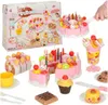 A collection of toy fruit cake pieces and accessories, including candles, fruits, and a knife, arranged on a white background. Podgląd zdjęcia produktu