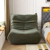 A green beanbag chair is placed next to a bed in a bedroom. Produktbild-Vorschau