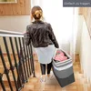 A woman walking down stairs carrying a laundry basket. Produktbild-Vorschau