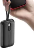 A hand holds a smartphone and a black power bank with integrated cables. Podgląd zdjęcia produktu