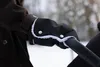 A close-up shot of a person's arm wearing a black hand warmer with white trim, attached to a stroller handle, in a snowy outdoor setting. Náhľad obrázku produktu