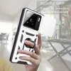 A hand holding a white and black phone case with a silver ring holder, with a blurred indoor background. Produktbild-Vorschau