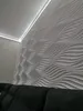 A modern living room with a textured white wall and a dark sofa. Produktbild-Vorschau