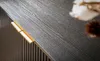 A close-up shot of a dark wood-grain sideboard with a golden handle, with a blurred cotton plant and a brown pom-pom in the background. Voir les images du produit