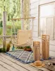 A porch scene with a hanging chair, rug, and decorative wooden lanterns. Produktbild-Vorschau