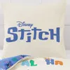 A close-up view of a cream-colored pillowcase with blue text and graphics, and another patterned fabric underneath. Produktbild-Vorschau