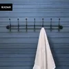 A black metal coat rack with seven hooks is mounted on a blue wooden wall. A beige towel is hanging from one of the hooks. Podgląd zdjęcia produktu