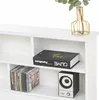 A close-up view of a white bookshelf with various items on its shelves, including a book, CDs, and a speaker. Podgląd zdjęcia produktu
