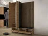A man in a suit walks past a modern entryway storage unit with wood and black accents, a bench, and a robotic vacuum cleaner on the floor. Náhled obrázku produktu