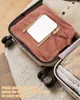 A compact mirror is placed on top of folded clothes inside an open suitcase. Produktbild-Vorschau