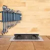 A retractable power outlet with USB ports is installed on a wooden surface, with a set of wrenches mounted on a wooden wall in the background. Produktbild-Vorschau