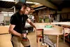 A man is using a cordless drill to assemble a wooden frame in a workshop. Produktbild-Vorschau