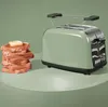 A green toaster sits next to a stack of toast with butter on a green surface. Anteprima dell’immagine prodotto