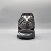 The back view of a black ASICS Gel-Kayano 14 sneaker against a plain gray background. Produktbild-Vorschau