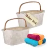 Two white laundry baskets with brown handles are shown, with a stack of rolled towels in colorful shades of pink, orange, blue, and yellow in the foreground. A tag on one of the baskets reads '2er Set'. Produktbild-Vorschau