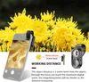 A smartphone with a clip-on microscope attachment is shown against a backdrop of yellow chrysanthemums. The screen displays a magnified view of what appears to be an insect's leg. Text and diagrams explain the working distance of the microscope. Produktbild-Vorschau