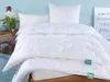 A neatly made bed with white bedding, including pillows and a duvet, in a room with a light blue wall. Produktbild-Vorschau