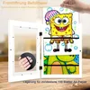 A white picture frame is open, revealing children's artwork inside. A hand is shown inserting artwork into the frame. Produktbild-Vorschau