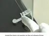 A close-up of a hand wearing a white glove installing a metal fitting onto a glass panel. Anteprima dell’immagine prodotto
