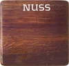 A close-up of a wooden surface with the word "NUSS" printed on it. Produktbild-Vorschau
