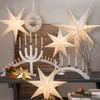 A collection of illuminated paper stars and candle holders arranged on a table, creating a festive holiday display. Podgląd zdjęcia produktu