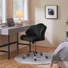 A black office chair is placed next to a desk with a laptop and a lamp, in a room with a bed visible. Produktbild-Vorschau