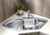 A stainless steel corner sink with a faucet and a small potted plant on the countertop. Podgląd zdjęcia produktu