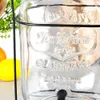 Close-up of a glass beverage dispenser with embossed text. Produktbild-Vorschau
