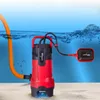 A red and black submersible pump with an orange hose and a float switch submerged in blue water, resting on a sandy bottom. Podgląd zdjęcia produktu