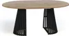 A close-up view of an oval dining table with a light wood top and a decorative black metal base. Podgląd zdjęcia produktu