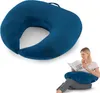 A U-shaped pillow is shown in two contexts: a close-up view on a white background and a woman using it while reading on a sofa. Produktbild-Vorschau