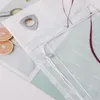 A close-up view of a white curtain with a silver grommet and a purple embroidered pattern. There are also slices of grapefruit visible in the background. Produktbild-Vorschau