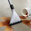 A vacuum cleaner nozzle is shown cleaning up a spilled coffee mug on a tiled floor. Náhled obrázku produktu