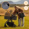 A woman pushing a stroller in a grassy field with mountains in the background. Produktbild-Vorschau