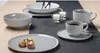 A table setting with plates, bowls, and cups arranged on a dark runner. Anteprima dell’immagine prodotto