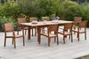 A wooden garden dining set with a table and chairs on a patio, surrounded by greenery. Produktbild-Vorschau
