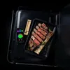 A cooked and sliced steak is presented in a black tray next to a smartphone displaying a cooking app and a meat thermometer. Náhled obrázku produktu