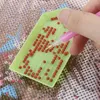 A hand is using a tool to pick up red beads from a green tray, which is placed on a diamond painting canvas. Náhľad obrázku produktu