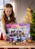 A young girl is holding an advent calendar with horse-themed toys in a festive setting with a Christmas tree. Produktbild-Vorschau