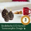 Three pine cone shaped LED candles are displayed on a white surface next to a bowl of cookies and a red polka dot mug. Produktbild-Vorschau