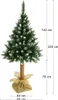 A full-length shot of an artificial Christmas tree with snow-like flocking and pinecones, standing in a burlap sack base. Dimensions are indicated with measurement lines and text. Náhľad obrázku produktu
