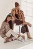 Two women posing in winter fashion, one sitting on a stool and the other on the floor, with winter boots and accessories. Produktbild-Vorschau