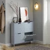 A light blue shoe cabinet with multiple compartments is placed in a hallway against a gray wall, with a coat hanging on a hook to the left and a lamp on the wall to the right. Náhled obrázku produktu