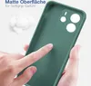 A hand is touching a green phone case, highlighting its matte texture and soft grip. Cotton balls are in the background, suggesting softness. Produktbild-Vorschau