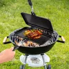 A person is grilling steaks and vegetables on a charcoal grill outdoors. Produktbild-Vorschau