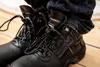 Close-up of black work boots with blue jeans. Náhled obrázku produktu