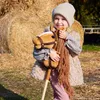A young girl is holding a hobby horse in front of hay bales. Anteprima dell’immagine prodotto