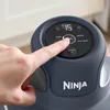 A close-up of a person's finger pressing a button on the control panel of a Ninja air fryer. Anteprima dell’immagine prodotto