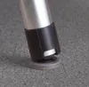 Close-up of the bottom of a metal leg with a black protective sleeve and a gray rubber foot, resting on a speckled gray surface. Náhľad obrázku produktu